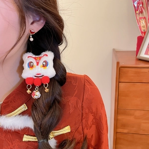 Detail of red lion dance hair clip and heart pearl earrings with traditional red dress
