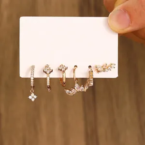Detail view of 5-piece gold earring set with zircon flowers and cuffs on a card
