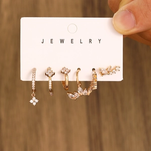 Detail view of 5-piece gold earring set with zircon flowers and cuffs on a card