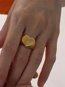 Close-up of a chunky gold heart-shaped ring styled on a finger with a polished finish