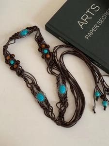 Detail of bohemian wax cord belt with turquoise stones and vintage metal lace carving