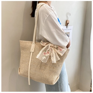 Detail of straw tote bag showing large capacity and delicate lace bow embroidery