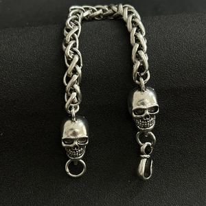 Close-up of hip-hop men's chunky braided chain bracelet featuring detailed skull heads