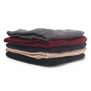 Stack of thick knit beanies in five colors showing warm textured winter headwear details