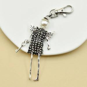 Close-up of angel keychain with white pearl head and black rhinestone dress detail