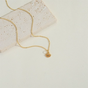 Golden evil eye necklace with colorful zircon pendant on a beige stone block background