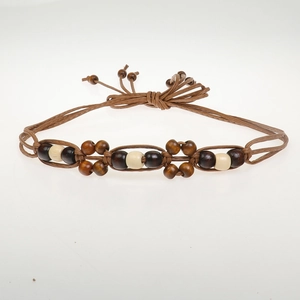 Detail of woven brown rope belt featuring decorative wooden beads in flower patterns