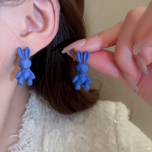Detail view of blue matte bunny stud earrings showing flocked texture on model ear