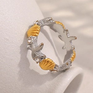 Close-up of 18K gold starfish ring with white rhinestones and shell ocean detail