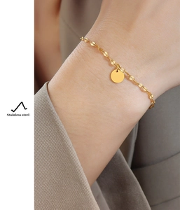 Detail of 18K gold plated stainless steel bracelet with minimalist circular pendant on wrist