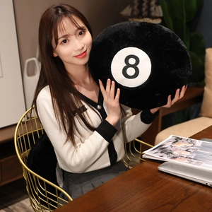 Detailed view of large black number 8 billiards plush pillow held by a person in a cozy room