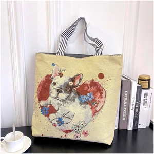 Close-up of canvas tote bag with French Bulldog and floral embroidery on a desk