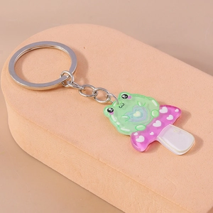 Close-up of green frog on purple mushroom resin keychain with heart detail