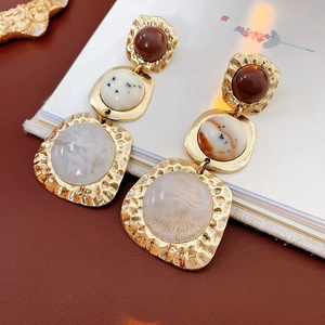Detailed view of vintage hammered gold earrings with marbled resin beads on a book