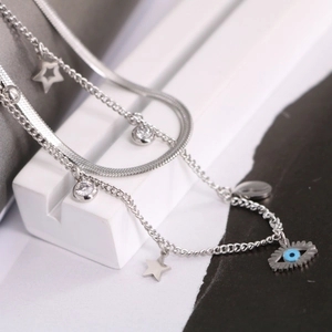 Double-layered silver necklace with blue evil eye pendant and stars on a geometric block