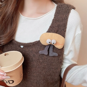 Detail of funny plush brooch with big eyes and grey legs on a brown sweater