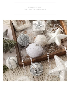 Flat lay of festive silver and white Christmas tree ornaments on a cozy knit blanket