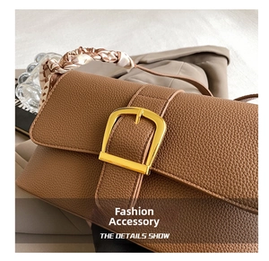 Detail view of brown pebbled leather bag with gold buckle and silk scarf handle