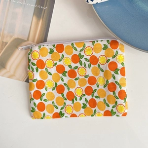 Detailed top view of a small floral fabric coin purse with orange fruit pattern and zipper