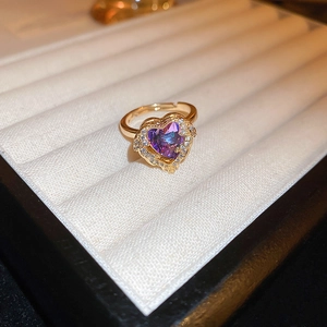 Close-up of golden heart ring with purple gradient stone and zircon pave setting