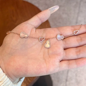 Rose gold hulu bracelet with shell inlay and hollow charms held in hand
