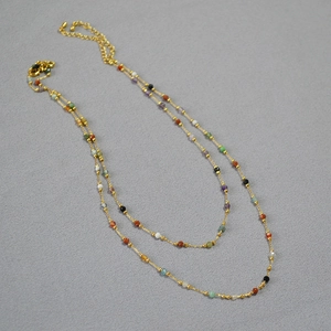Detail of colorful faceted stones on a delicate gold metal chain necklace with clasp