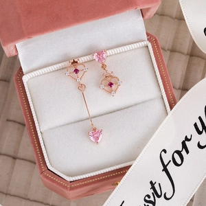 Detailed macro view of pink heart zircon earrings with gold crown accents in a velvet box