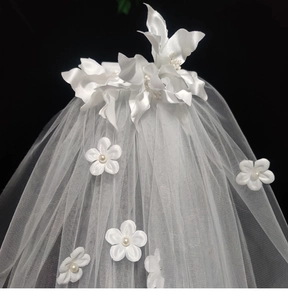 Detailed close-up of white bridal veil featuring delicate 3D fabric flowers and pearls