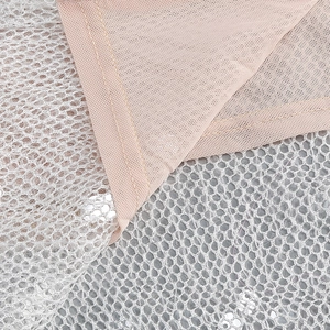 Makroaufnahme von Pailletten-Netzstoff über rosa Futter eines Abendkleid-Details