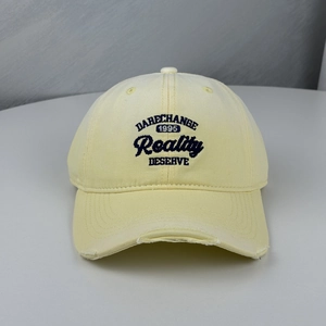 Close-up of distressed cream baseball cap featuring vintage embroidery and wide brim
