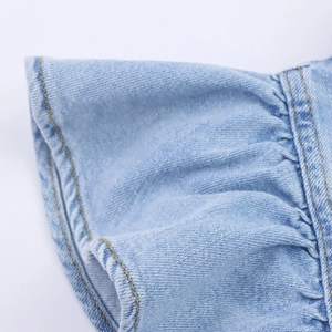 Macro-opname van lichtblauwe denim met ruches en gele contraststiksels