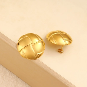 Macro detail of golden round stud earrings featuring an embossed woven grid pattern texture