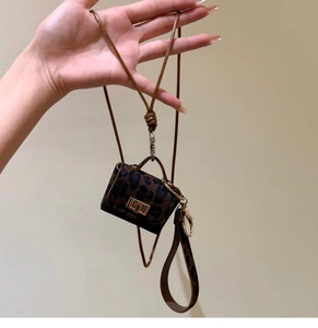 Detail of a mini leopard print pendant with gold clasp and long woven neck strap