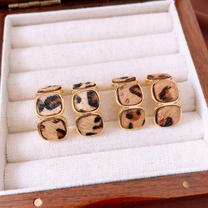 Detail shot of leopard print gold earrings arranged in a premium velvet jewelry box