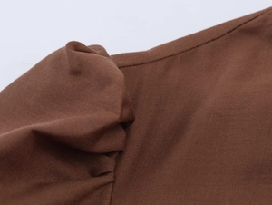Gros plan sur les détails plissés de l'épaule d'une robe longue brodée marron