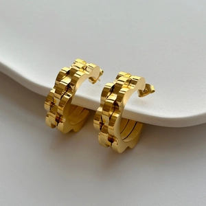 Polished 18k gold plated C-shaped earrings with unique chain texture on a white stand