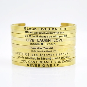 Macro detail of gold 4mm stainless steel cuff bracelets with motivational engravings