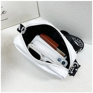 Detail view of white nylon crossbody bag interior showing storage for phone and sunglasses