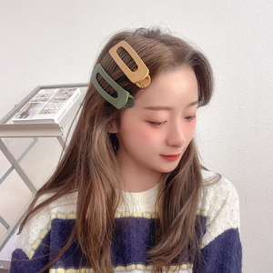 Detailed view of matte geometric hair clips in dark green and mustard yellow on hair