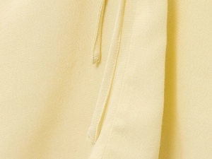 Close-up of pale yellow textured fabric with finely stitched chiffon drawstring detail