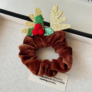 Détail d'un chouchou de Noël en velours avec bois dorés et pompons rouges festifs