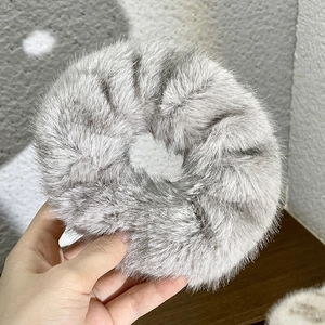 Close-up of grey plush scrunchie made of soft faux fur being held for texture detail
