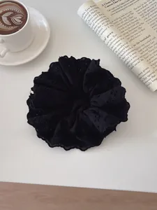 Detailed close-up of premium black lace scrunchie with intricate embroidery on a desk