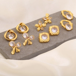 Detailed arrangement of five pairs of gold-plated earrings with clear crystals on stone base