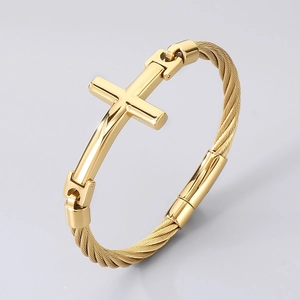 Gros plan d'un bracelet câble doré avec croix polie et détail de charnière précis