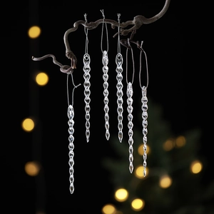 Sparkling clear acrylic icicle Christmas ornaments hanging on a rustic branch with bokeh background