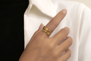 Detail of a minimalist golden lightning bolt ring on finger with an adjustable design