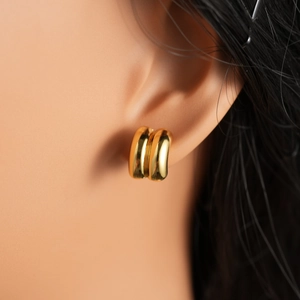 Close-up of minimalist 18k gold geometric C-shaped stud earrings worn on an ear