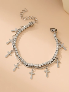Macro view of silver layered chain bracelet featuring rhinestone star and cross charms