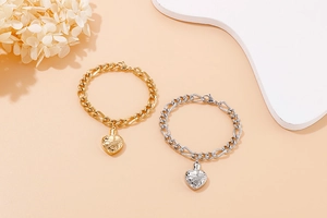 Detail of gold and silver heart pendants with engraved patterns on Figaro chain bracelets